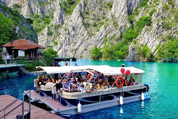 Tourists board a spacious pontoon boat at the lively dock of Matka Canyon.