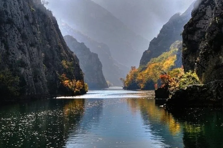 A moody, sun-dappled view of Matka Canyon with autumn colors on the trees.